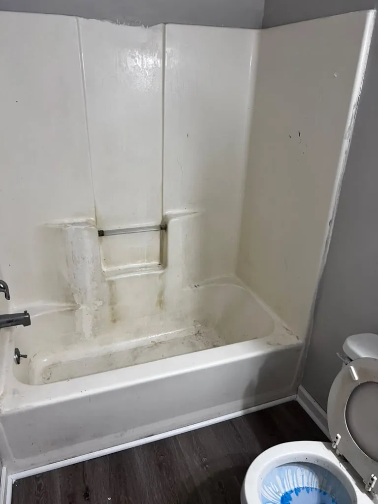 Dirty fiberglass bathtub and shower walls before deep cleaning