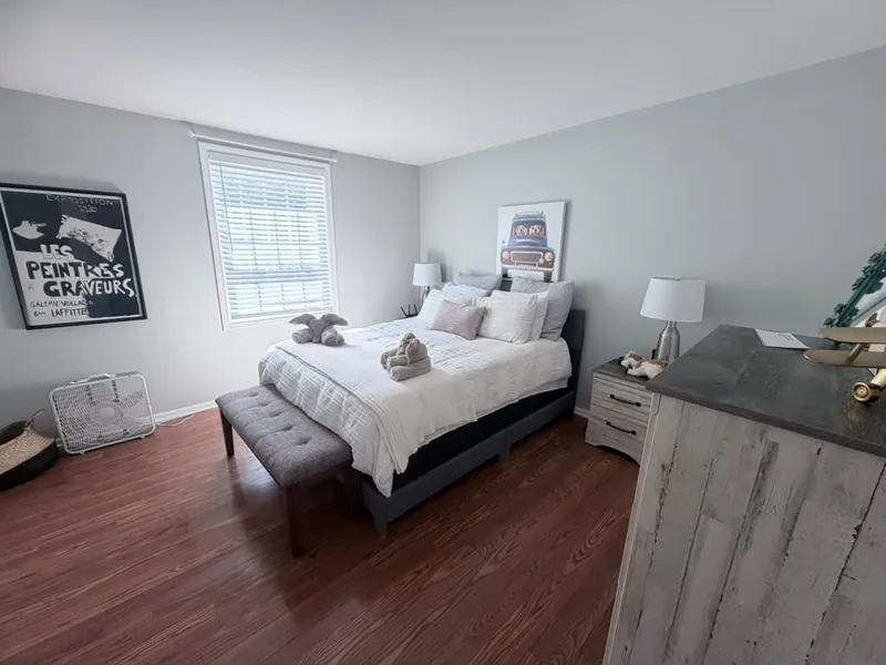 Tidy bedroom with polished hardwood floor and made bed after cleaning
