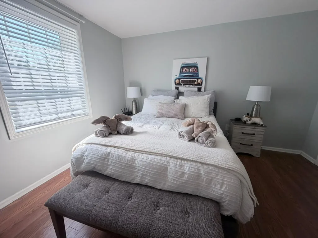 Bright rental bedroom with crisp white bedding and towel animals after cleaning