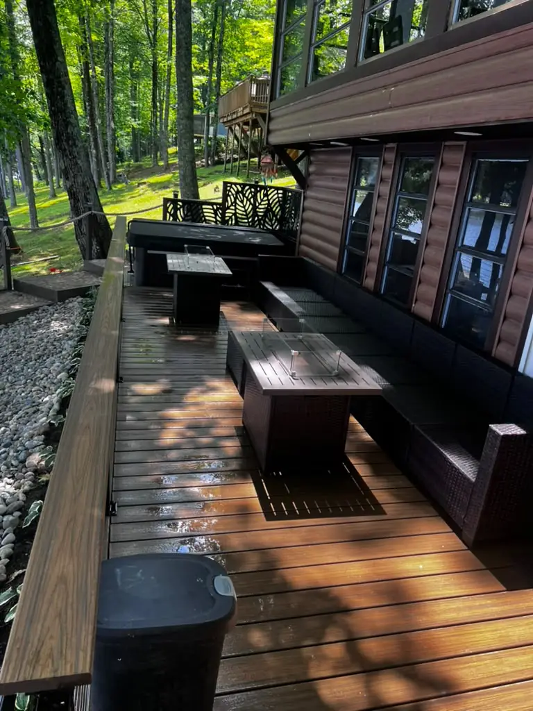 Composite deck with wicker seating and fire tables after power washing at a lakeside cabin