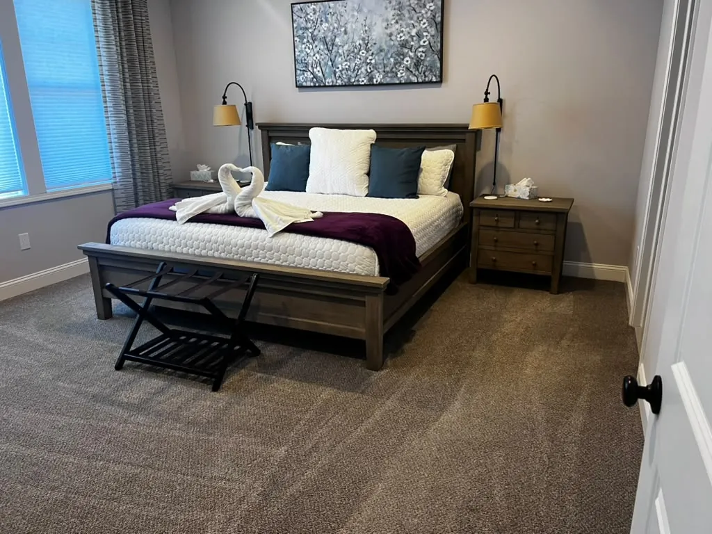 Master bedroom with swan-folded towels and freshly vacuumed carpet after a recurring cleaning