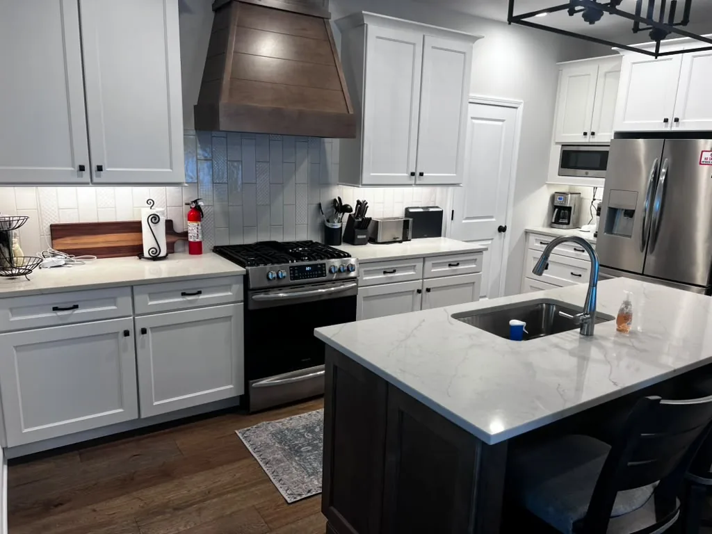 Spotless white kitchen with quartz island and stainless appliances after cleaning
